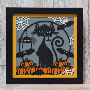 Halloween decor shadowbox layered paper cats, spiders, and pumpkins.