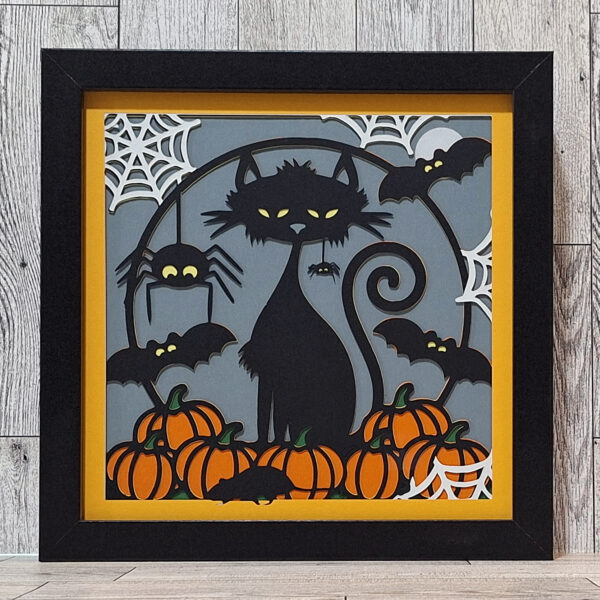 Halloween decor shadowbox layered paper cats, spiders, and pumpkins.