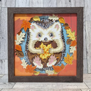 Adorable happy hedgehog holding leaves, layered paper art in frame