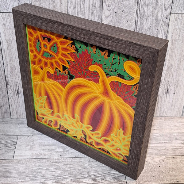 Angled view of pumpkin patch layered paper shadow box.
