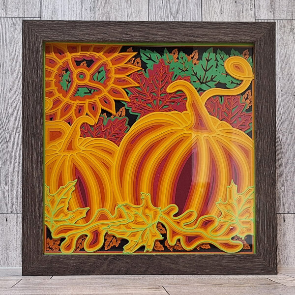 Pumpkins and fall leaves shadow box of layered paper in brown frame.