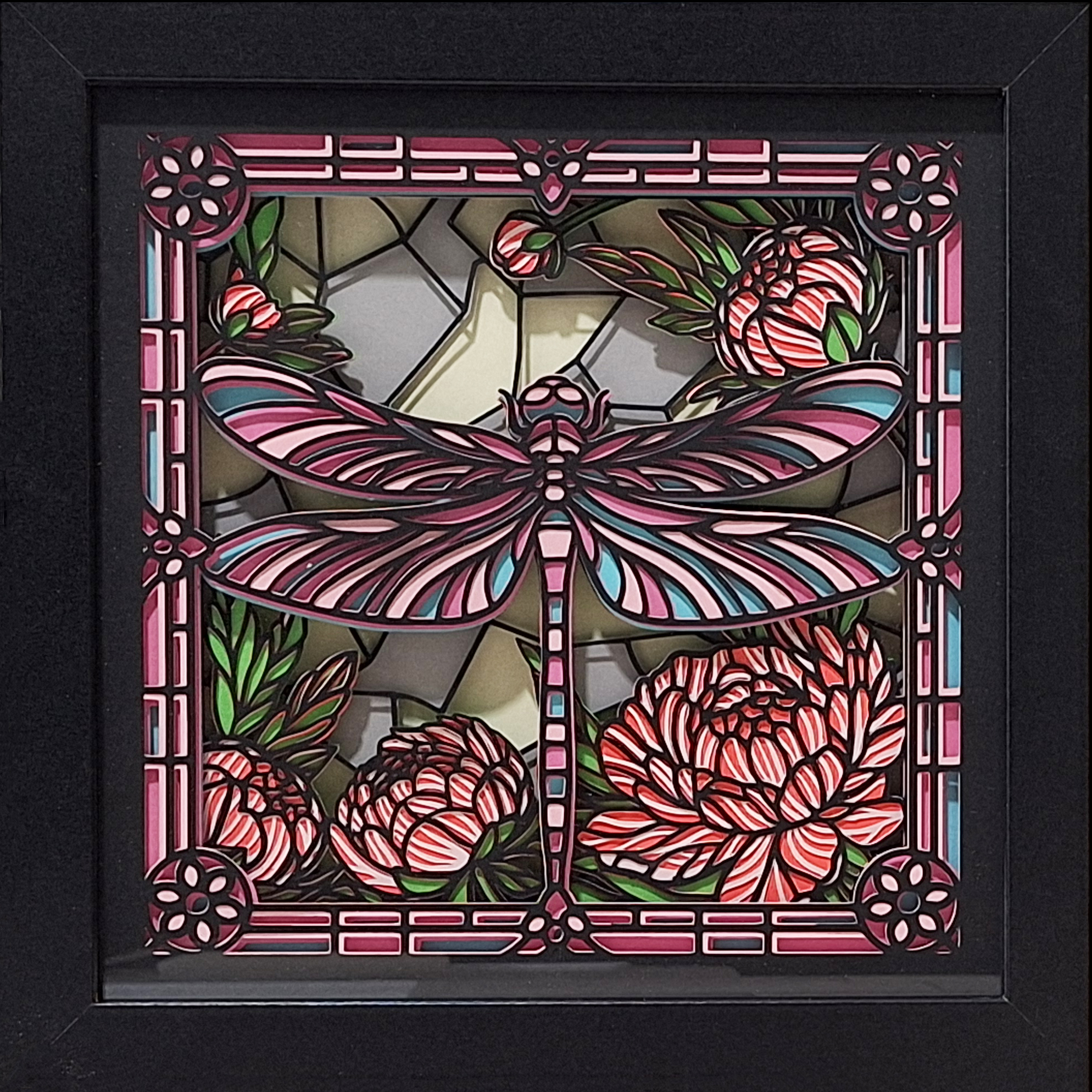 Dragonfly made of layers of intricately cut paper in a black frame
