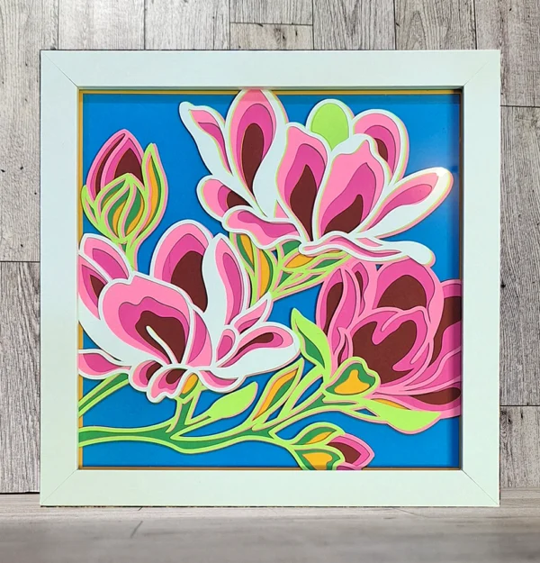Magnolia flower made of layered paper in a white frame.