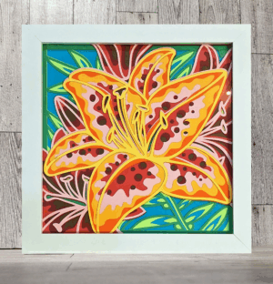 Tiger lily flower made of layers of intricately cut paper in a white frame